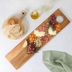 a wooden cutting board topped with lots of cheese and meat next to a bottle of wine