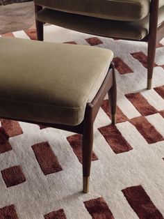 two brown chairs sitting next to each other on top of a white and red rug