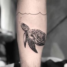 a black and white photo of a sea turtle tattoo on the left calf's leg