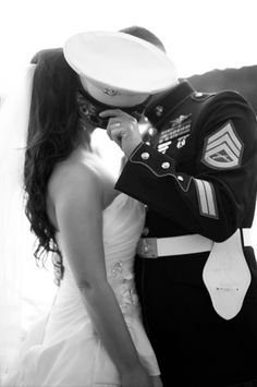 a bride and groom kissing each other in front of an american flag at the end of their wedding day