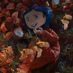 an animated doll is standing in front of some flowers and other things on the ground