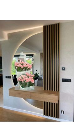 a vase with pink flowers sitting on top of a wooden table in front of a mirror