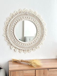 a white crocheted doily mirror hanging on the wall above a wooden dresser