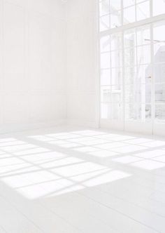 an empty room with large windows and white walls