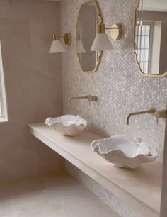 two sinks in a bathroom with mirrors and lights on the wall next to each other