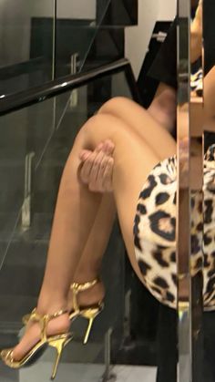 a woman in leopard print dress sitting on stairs with her legs crossed and feet up