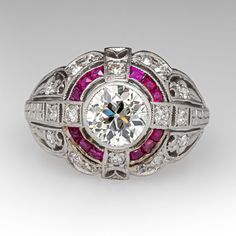 This fabulous circa 1920s ring features a pierced design with engraved details and is bordered with milgrain edging. The ring is centered with one (1) old European cut diamond set into a bezel setting. The ring is also accented with twelve (12), channel set, square French cut natural rubies and eighteen (18), bead set, old European/single cut diamonds. The ring measures 13.2mm at the top, rises 5.0mm above the finger, tapering to 2.0mm wide and 1.2mm thick at the base of the shank. The ring is currently a size 5. One of the diamonds has an unnoticeable chip. Classic Ruby Ring With Vvs Clarity In Diamond White, Classic Ruby Ring With Prong Setting In Platinum, Classic Platinum Ruby Ring With Prong Setting, Classic Platinum Ruby Ring With Brilliant Cut, Classic Platinum Ruby Ring With Center Stone, Classic Platinum Ruby Ring With Diamond Cut, Classic Ruby Ring With Prong Setting In Diamond White, Classic Ruby Ring With Diamond White Prong Setting, Vintage Platinum Ruby Ring For Formal Occasions