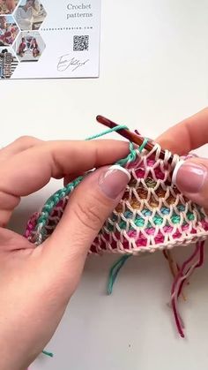 two hands are working on a piece of crochet