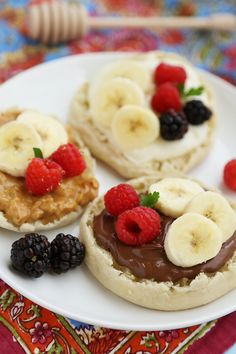 three small pastries on a white plate with berries and raspberries