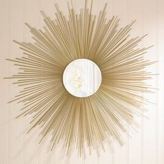 a sunburst shaped mirror mounted on the wall above a white table and chair