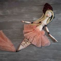 a doll is laying on the floor wearing a pink dress