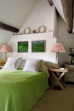 a bedroom with green bedding and two lamps