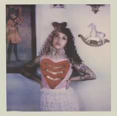 a woman with tattoos holding a heart in front of her face and wearing a costume