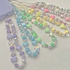 several beads and charms on a table next to a cell phone