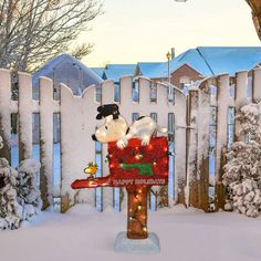 a mailbox decorated with christmas lights and stuffed animals is in the snow near a fence