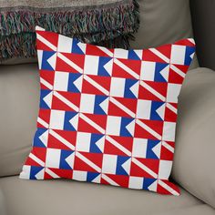 a red, white and blue pillow sitting on top of a couch next to a throw pillow