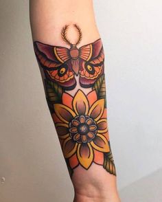 a woman's arm with an owl and flower tattoo design on the left forearm