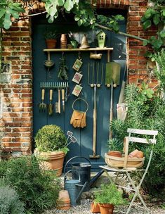 an outdoor garden with potted plants and gardening utensils hanging on the wall