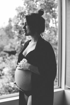 a pregnant woman standing in front of a window