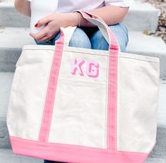 a woman sitting on steps holding a pink and white tote bag with the letter k in it