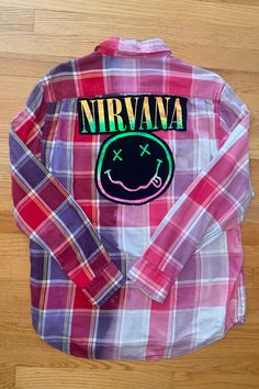 One-of-a-kind Flannel featuring the legendary, one and only, Nirvana! Thrifted and Prewashed 100% cotton button-up with a t-shirt print stitched to the back.   Size Large  Measurements: ♥  Shoulders: 19.25" ♥  Chest: 24" ♥  Sleeve: 25.25" ♥  Length: 26" . . . . . . . . . . . . . . . . . . . . . . . . . . . . . . . . . . . . . . . . . . . . . Handmade ♥ Thrifted ♥ Recycled ♥ Upcycled These button-ups are created with a thrifted button-up and shirts that need a second life and once they are combin Cotton Patchwork Shirt For Streetwear, Alternative Style Cotton Top For Fall, Cotton Long Sleeve Shirt With Patches, Cotton Top For Fall Festival, Cotton Grunge Shirt For Spring, Spring Cotton Grunge Shirt, Casual Pink Cotton Flannel Shirt, Spring Grunge Cotton Shirt, Cotton Patchwork Button-up Flannel Shirt