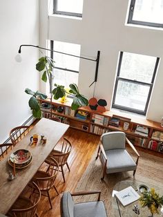 an overhead view of a living room and dining area with chairs, tables, bookshelves and windows