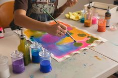 a person painting on a piece of paper with watercolors and paintbrushes