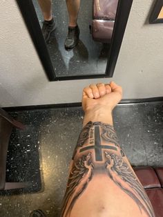 a man's arm with a cross tattoo on it and his reflection in the mirror