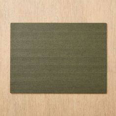 a close up of a green place mat on a wooden surface with space for text