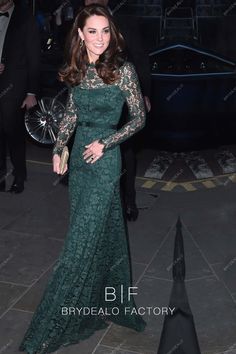 a woman in a long green dress standing next to a black car at an event