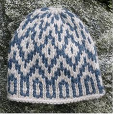 a blue and white knitted hat sitting on top of a rock