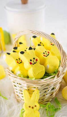 some yellow peepies are in a basket on the table next to eggs and other decorations