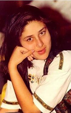 a young woman sitting down with her hand on her chin and looking at the camera