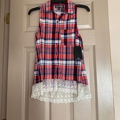 a red and white plaid shirt hanging on a door with lace around the hemming