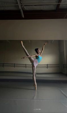 a ballerina is standing on one leg in an empty room