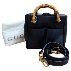 This vintage GUCCI mini 2-way bamboo crossbody bag is crafted of calfskin leather in dark navy featuring gold toned hardware and mini bamboo handles. The front of this mini bag also features two slip pockets. Top magnetic snap flap closure opens to a dark navy fabric interior featuring a zippered pocket. This mini bag also comes with a crossbody strap of the same leather. Made in Italy. Measures approximately 6 x 5.5 x 3 inches Strap drop 19 inches. Comes with dustbag and crossbody strap. Condit Gucci Black Shoulder Bag With Bamboo Handle, Leather Crossbody Shoulder Bag With Bamboo Handle, Gucci Black Bag With Bamboo Handle, Black Gucci Bag With Bamboo Handle, Classic Gucci Bag With Bamboo Handle, Gucci Shoulder Bag With Bamboo Handle For Daily Use, Gucci Vintage Bag, Gucci Mini, Gucci Crossbody Bag