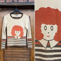 "Vintage 1960's \"Orphan Annie\" Glam Mod Pop Art Knit Long Sleeve T-Shirt. No Size Tag. Please check the measurements below. Good vintage condition. Fading and some very damage. (see photos) The label is \"Varsity\". Original 1960's. Long sleeve fitted T shirt with pop art Orphan Annie. All Sales Final. Please ask any questions before purchase. Take a look at our Store for more Vintage Clothing - VintageOnHollywood. MEASUREMENTS Shoulder to Shoulder: 14 1/2\" Underarm to Underarm: 16\" Outer Sl Vintage Screen Print Tops For Fall, Vintage Screen Printed Tops For Fall, Retro Graphic Print Tops For Fall, Retro Crew Neck Top With Retro Print, Retro Long Sleeve Tops With Screen Print, 1970s Long Sleeve Tops With Retro Print, 1970s Style Long Sleeve Tops With Retro Print, 1970s Retro Print Long Sleeve Tops, White Vintage Tops With Retro Print