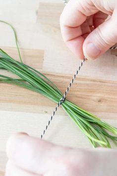 someone stringing up some green grass on a wooden board