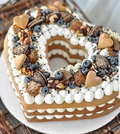 a cake with white frosting, blueberries and nuts in the shape of a heart