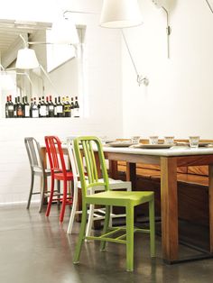 a dining room table with four chairs around it and bottles on the wall in the background