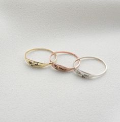 three gold and silver rings with writing on them sitting on a white surface in front of a plain background