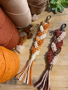 three tasselled key chains sitting on top of a wooden table next to potted plants