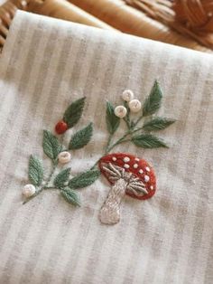 a close up of a piece of cloth with flowers and leaves embroidered on it in front of a basket