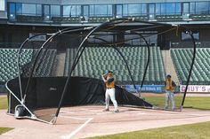 two baseball players are practicing in the batting cage