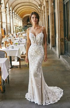 a woman in a white wedding dress standing next to a table with tables and chairs