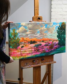 a woman is painting on an easel in front of a white brick wall and ceiling