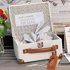 an open suitcase sitting on top of a wooden table next to books and papers with tags