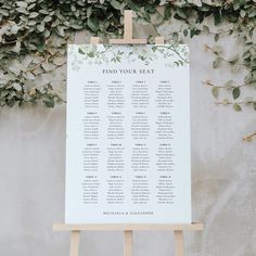 an easer with seating cards on it next to a wall covered in greenery