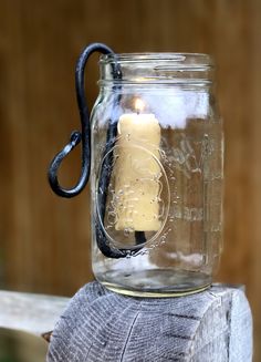 a mason jar with a candle in it sitting on top of a piece of wood