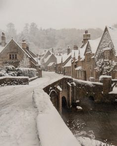 a snow covered street with buildings and a river running through it in the middle of winter